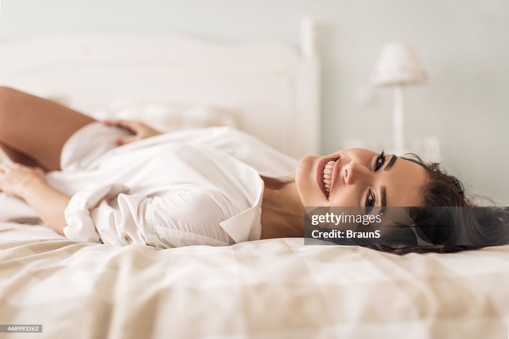 Glückliche Frau entspannend auf Bett, Blick in die Kamera.