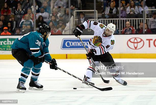 Nick Leddy of the Chicago Blackhawks passes the puck under the stick of Bracken Kearns of the San Jose Sharks during the first period at SAP Center...