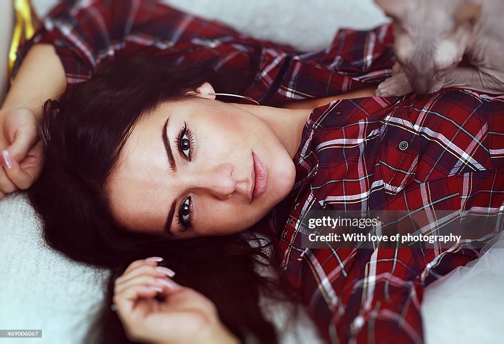 Beautiful woman in a plaid shirt with a sphinx cat