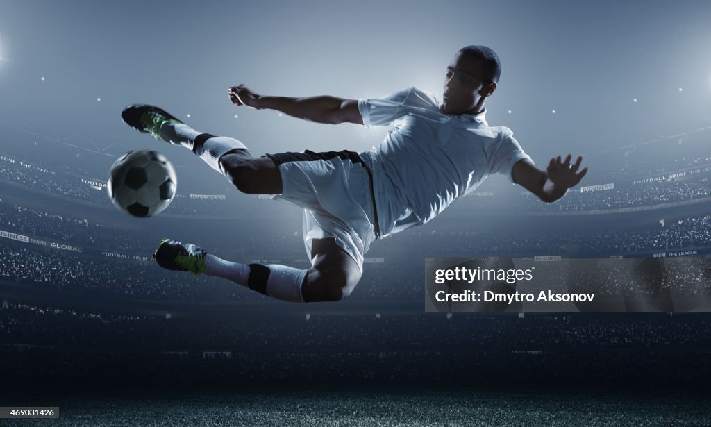 Soccer player kicking ball in stadium