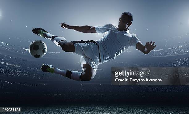 soccer player kicking ball in stadium - football player stock pictures, royalty-free photos & images