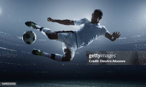 soccer player kicking ball in stadium - football players stock pictures, royalty-free photos & images