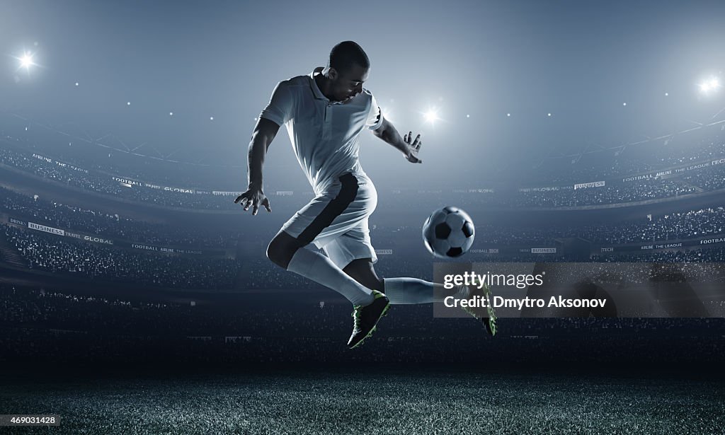 Soccer player kicking ball in stadium