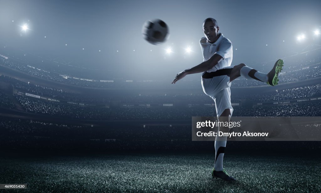 Soccer player kicking ball in stadium