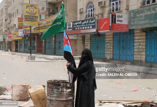 Yemeni woman holds the flags of Saudi Arabia and Yemens southern separatist movement in the southern city of Aden on April 9, 2015 in support of the...