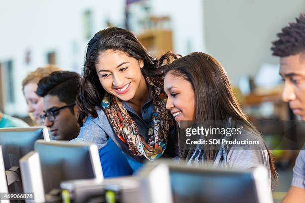 happy hispanic teacher assisting high school students with computers. - high school stock pictures, royalty-free photos & images
