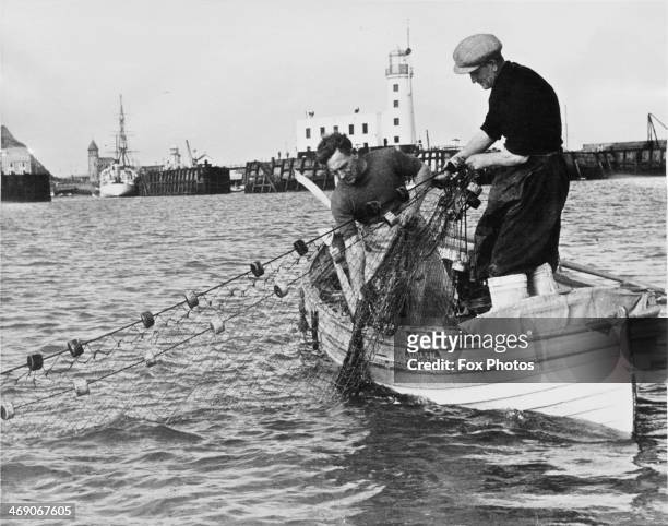 Salmon fishermen George Smalley and Robin Messruther hauling one of their nets into their boat, Molly, Scarborough, North Yorkshire, 31st July 1952....