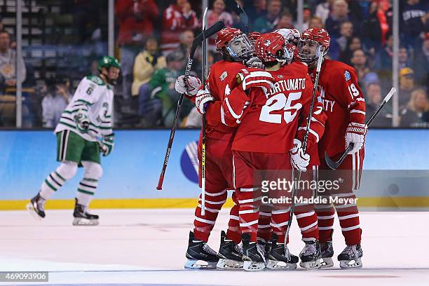 Brandon Fortunato and Robbie Baillargeon congratulate Brandon Hickey of the Boston Terriers after he scored against North Dakota during the first...