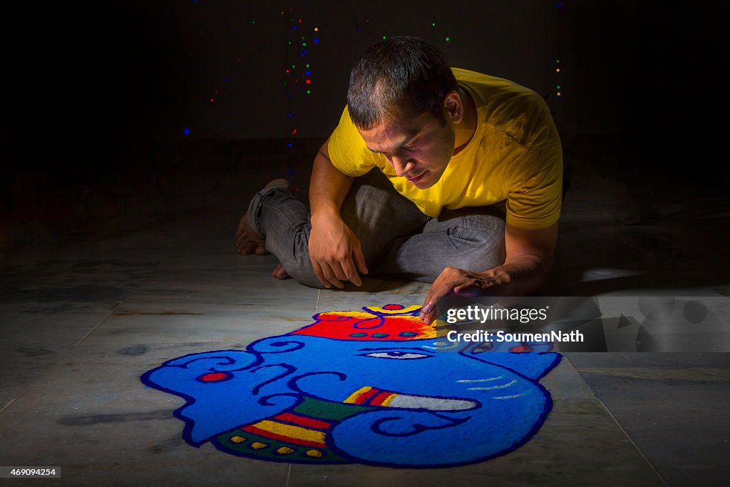 Young man making Rangoli on the occasion of Diwali
