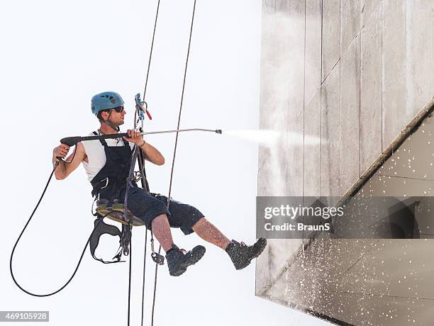 manuale operaio pendere alto e lavare un edificio. - in cima foto e immagini stock