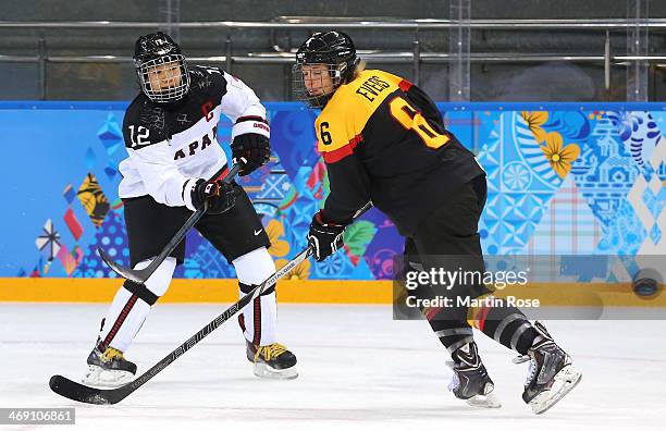 Chiho Osawa of Japan fires the puck against Bettina Evers of Germany in the first period during the women's Ice Hockey Preliminary Round Group B game...