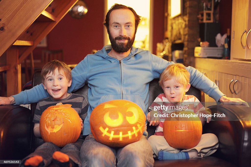 Happy father and sons with carved pumpkins