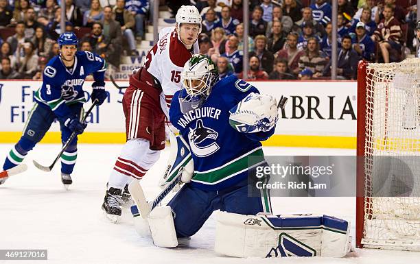 Goalie Eddie Lack of the Vancouver Canucks makes a glove save while Henrik Samuelsson of the Arizona Coyotes looks on in NHL action on April 9, 2015...