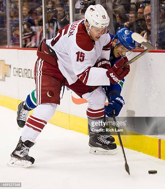 Henrik Samuelsson of the Arizona Coyotes and Luca Sbisa of the Vancouver Canucks battle for the puck along the end boards in NHL action on April 9,...