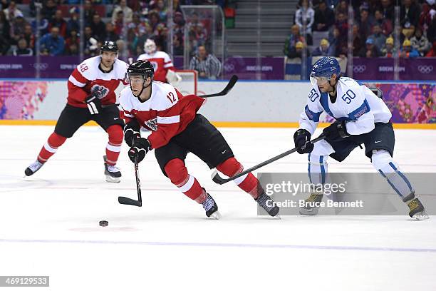 Michael Raffl of Austria skates with the puck against Juhamatti Aaltonen of Finland during the Men's Ice Hockey Preliminary Round Group B game on day...