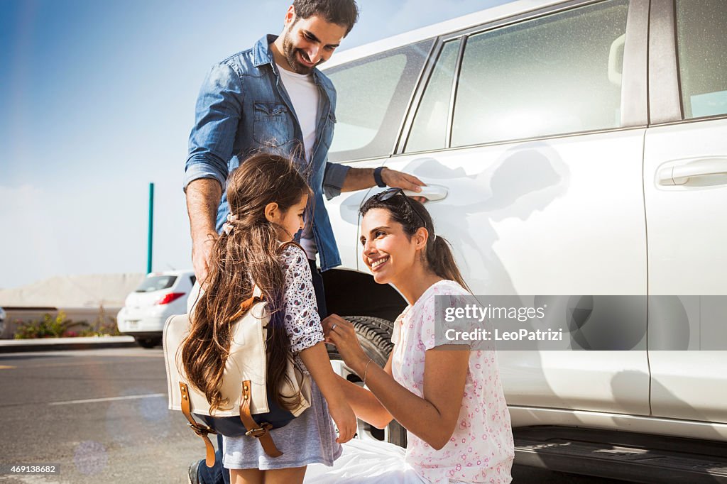 Young family taking daughter to school by car