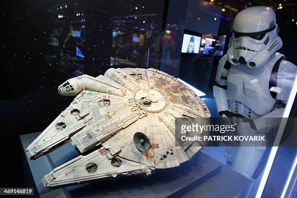 Performer dressed as a stormtrooper character looks at a model of the Millenium Falcon starship from the Star Wars film series, displayed during the...