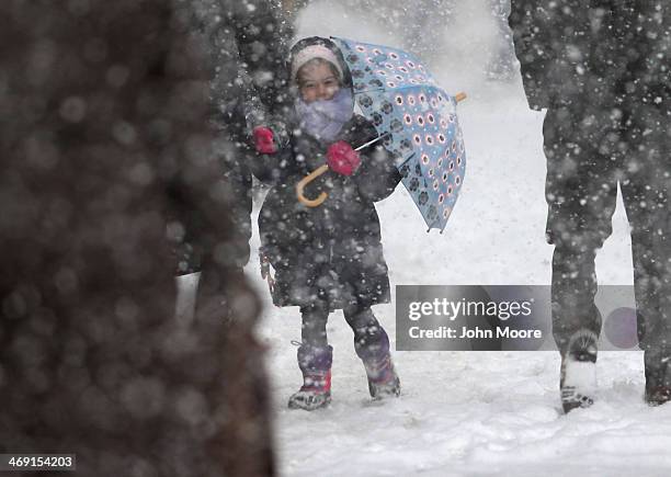 Child holds an umbrella as she walks to school during a snowstorm on February 13, 2014 in New York City. Heavy snow and high winds made for a hard...