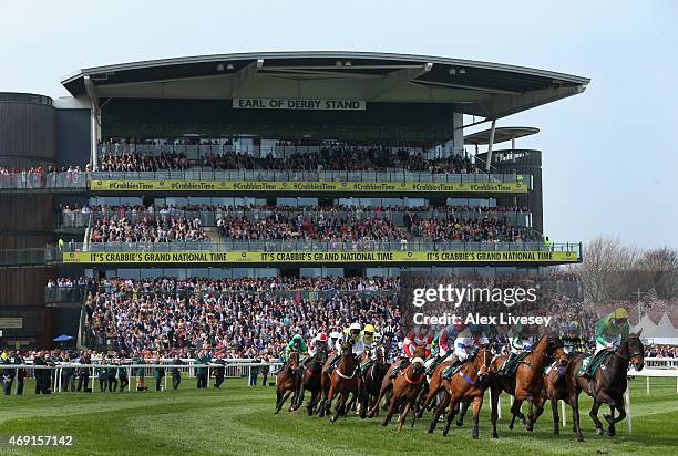 Horses and riders pass the grandstands during the Alder Hey Children's Charity Handicap Hurdle Race at Aintree Racecourse on April 10, 2015 in...