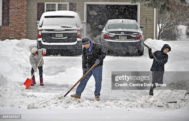 Simon Tack, center, and his children Marissa left, and Johnny shovel snow out of their driveway along Saxton Drive, in State College, Pa. A winter...