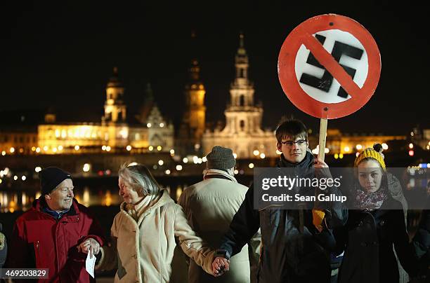 People, including one man holding a sign of a marked-through swastika, form a human chain in the city center as a statement against neo-Nazis on the...