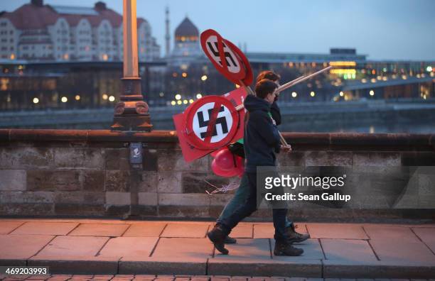 Anti-neo-Nazi activists carry signs showing smarked through swastikas before the creation of a human chain in the city center as a statement against...
