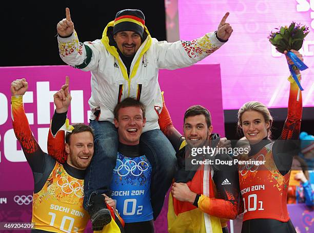 Gold medalists Tobias Arlt, Felix Loch, Tobias Wendl and Natalie Geisenberger of Germany lift their coach Georg Hackl in celebration during the...