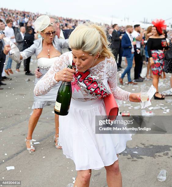 Racegoer drinks from a bottle of Champagne as she attends day 2 'Ladies Day' of the Crabbie's Grand National Festival at Aintree Racecourse on April...