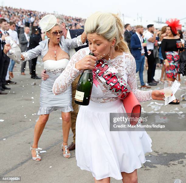 Racegoer drinks from a bottle of Champagne as she attends day 2 'Ladies Day' of the Crabbie's Grand National Festival at Aintree Racecourse on April...