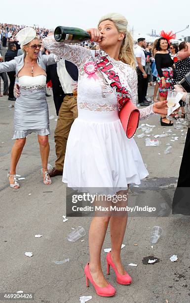 Racegoer drinks from a bottle of Champagne as she attends day 2 'Ladies Day' of the Crabbie's Grand National Festival at Aintree Racecourse on April...