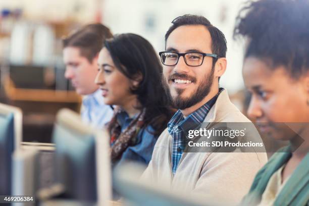 happy hispanic hipster man using comptuer in college computer class - adult stockfoto's en -beelden