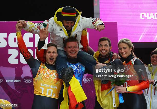 Gold medalists Tobias Arlt, Felix Loch, Tobias Wendl and Natalie Geisenberger of Germany lift their coach Georg Hackl in celebration during the...
