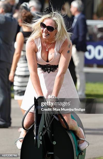 Racegoer rides on a horse racing simulator as she attends day 2 'Ladies Day' of the Crabbie's Grand National Festival at Aintree Racecourse on April...