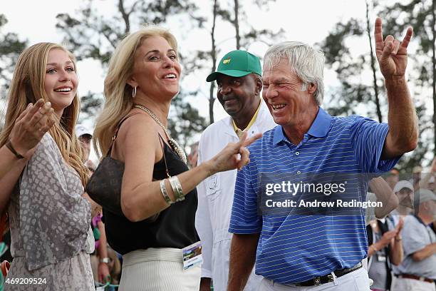 Ben Crenshaw of the United States waves to the gallery alongside his wife Julie and caddie Carl Jackson behind the 18th green after playing his final...