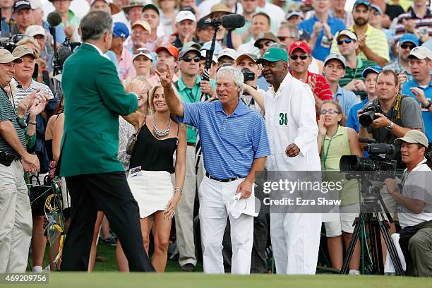 Ben Crenshaw of the United States waves to the gallery alongside his wife Julie and longtime caddie Carl Jackson behind the 18th green after playing...