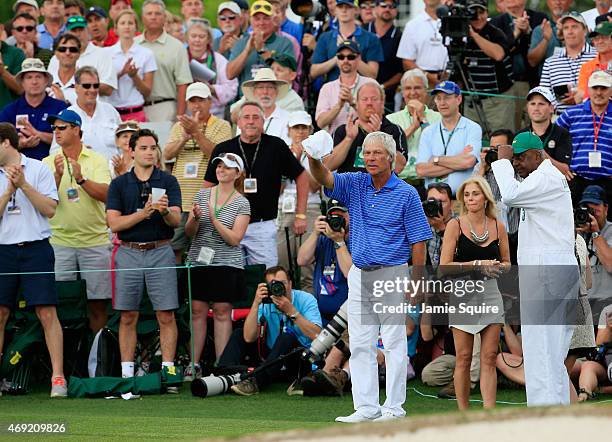 Ben Crenshaw of the United States waves to the gallery alongside his wife Julie and longtime caddie Carl Jackson behind the 18th green after playing...