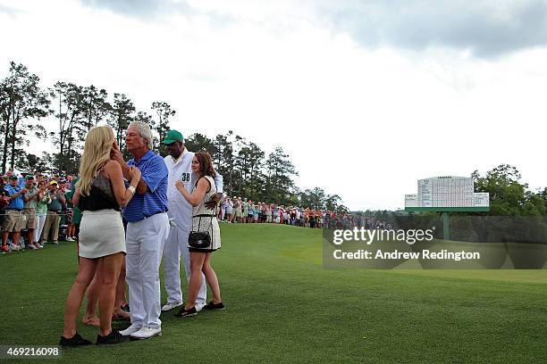 Ben Crenshaw of the United States waits alongside his wife Julie, their family and longtime caddie Carl Jackson behind the 18th green after playing...
