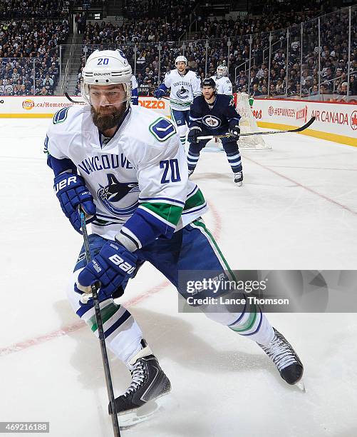 Chris Higgins of the Vancouver Canucks plays the puck along the boards as Jim Slater of the Winnipeg Jets looks on during first period action at the...