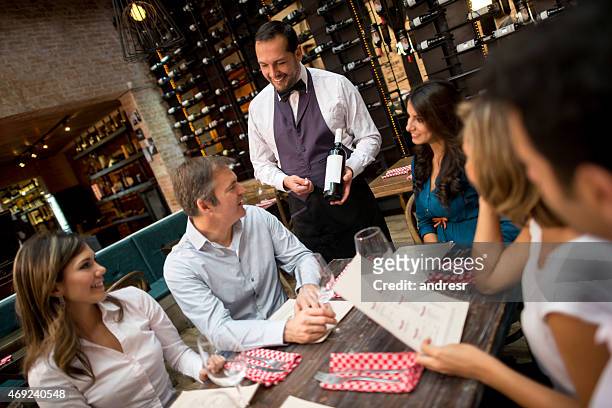 waiter suggesting a wine to a group of people - sommelier stockfoto's en -beelden