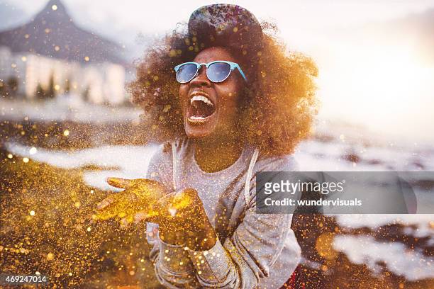 afro hipster girl laughing ecstatically while throwing gold glitter - vintage fashion stock pictures, royalty-free photos & images