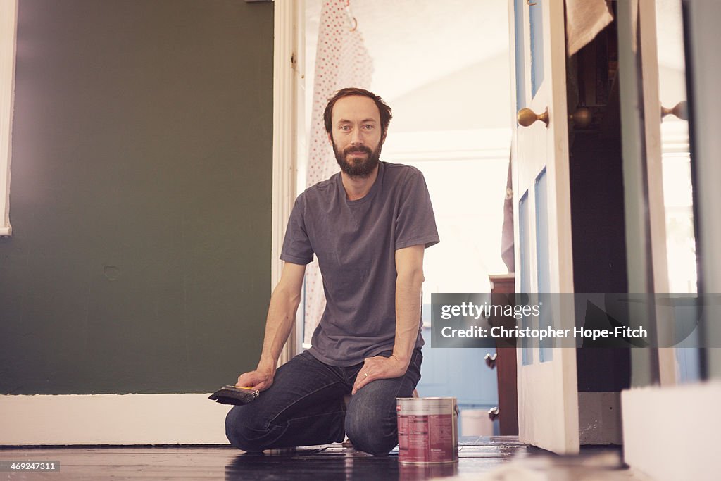 Man resting while painting a floor