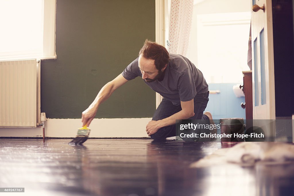 Man painting wooden floor