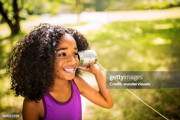 afro girl listening to a tin can phone in park - tin can phone stock pictures, royalty-free photos & images