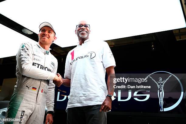 Nico Rosberg of Germany and Mercedes GP poses with Laureus Sport for Good Foundation Chairman Edwin Moses next to the F1 W06 in the team garage...