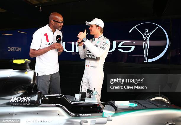 Laureus Sport for Good Foundation Chairman Edwin Moses chats with Nico Rosberg of Germany and Mercedes GP next to the F1 W06 in the team garage...