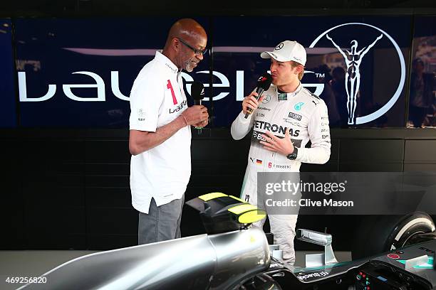 Laureus Sport for Good Foundation Chairman Edwin Moses chats with Nico Rosberg of Germany and Mercedes GP next to the F1 W06 in the team garage...