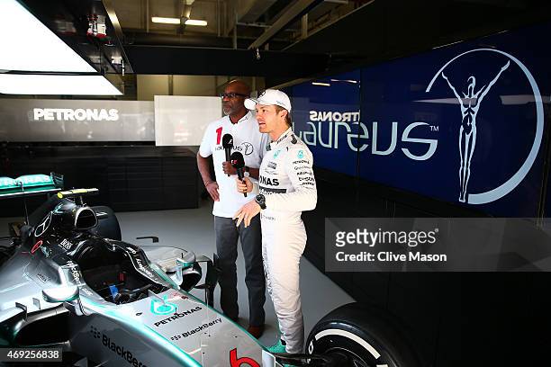 Laureus Sport for Good Foundation Chairman Edwin Moses chats with Nico Rosberg of Germany and Mercedes GP next to the F1 W06 in the team garage...