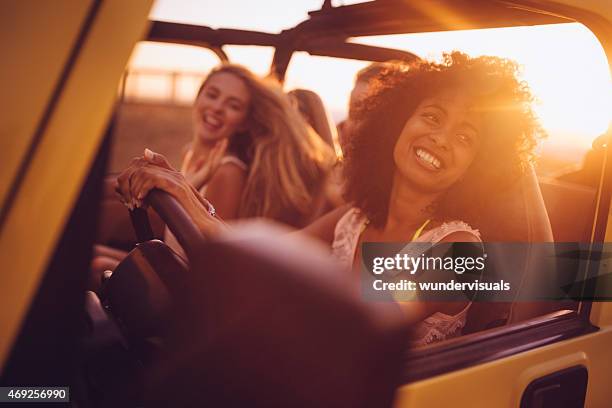 afro girl with friends on a road trip at sunset - car journey stockfoto's en -beelden