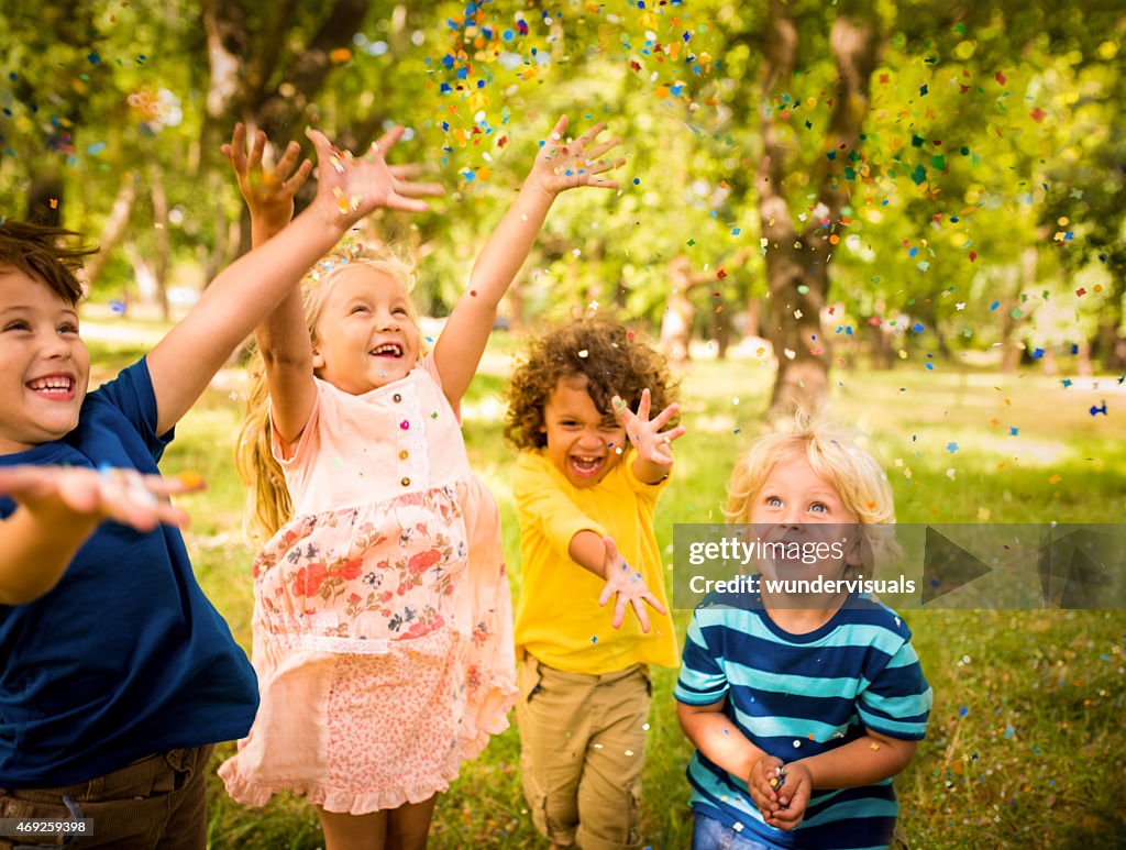 Happy child friends having fun with confetti in a park