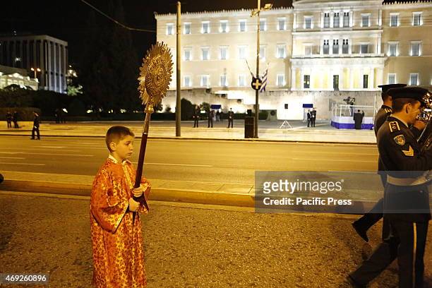 An altar server carries the ripidion past the Greek Parliament. Thousands of people lined the street for this year's Good Friday's Epitaphios...